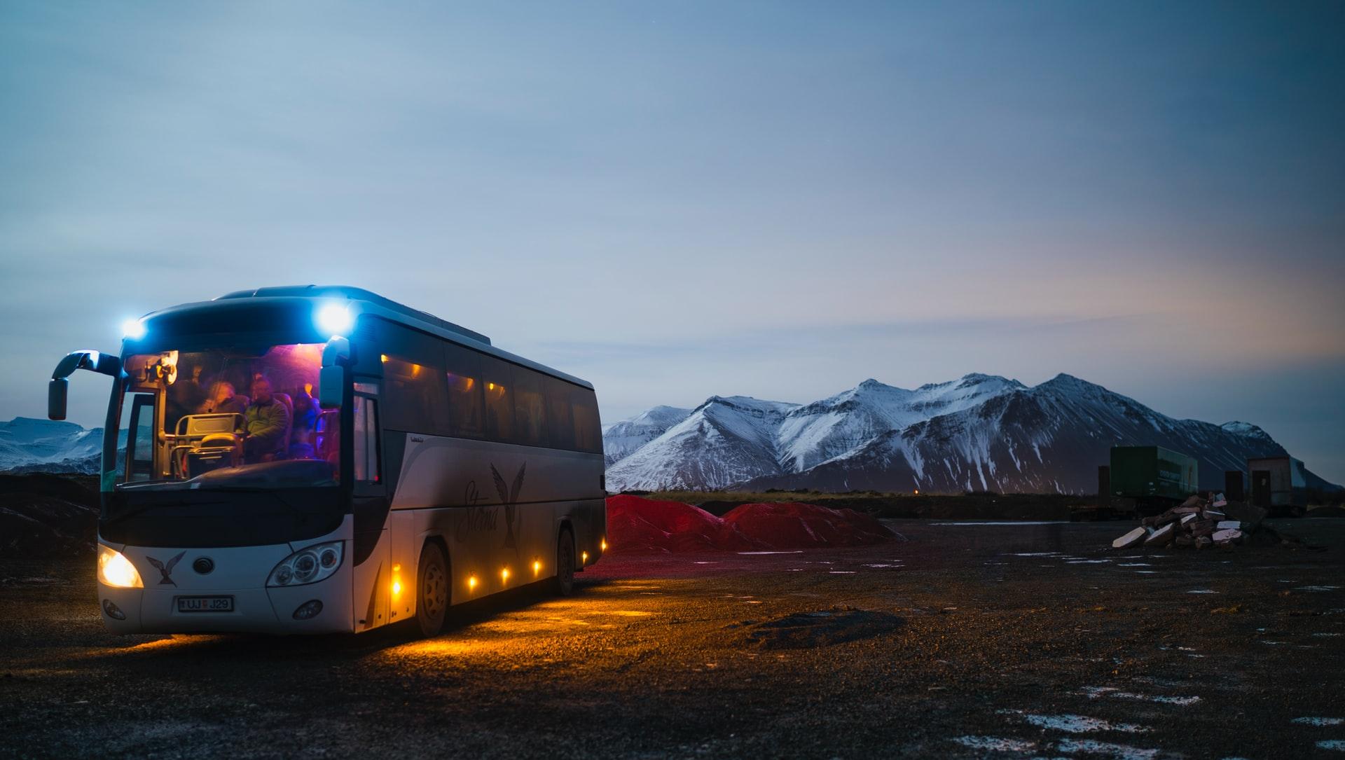 white and black bus running near the mountain